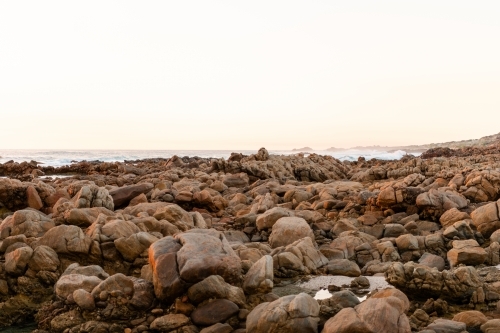 Ocean and rock view of rugged coastline at sunset