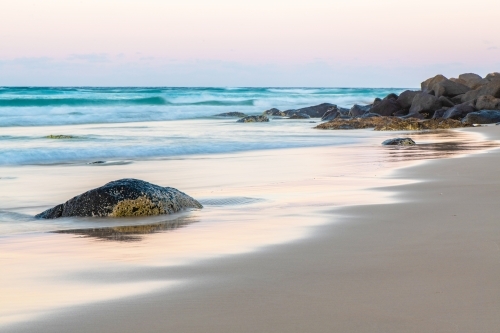 Ocean stone on beach with water reflections. - Australian Stock Image