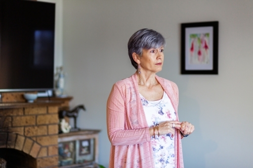 Oder woman looking to the side with copy space in her living room - Australian Stock Image