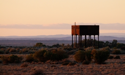 old water tank at sunrise with hills in background - Australian Stock Image