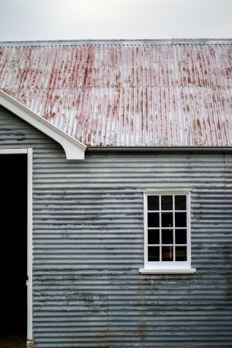 Old weathered corrugated iron farm shed with restored glass window