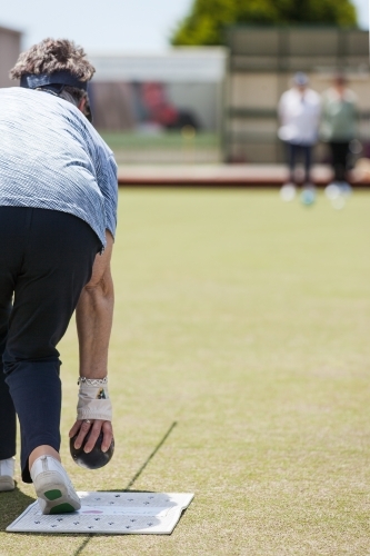 Older woman bowling on her backhand side - Australian Stock Image