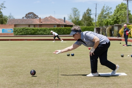 Older woman delivering a lawn bowl - Australian Stock Image