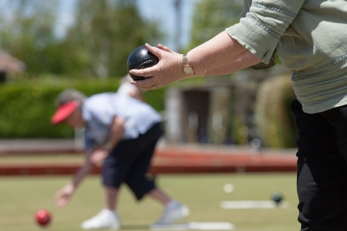 Older woman lining up her lawn bowl - Australian Stock Image