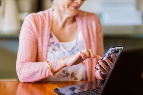 Older woman using mobile phone typing with one finger - Australian Stock Image