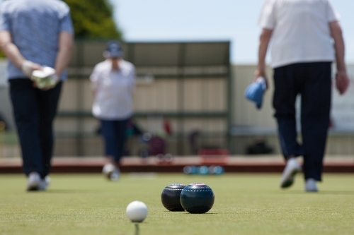 Older woman walking up and down the lawn bowls green - Australian Stock Image