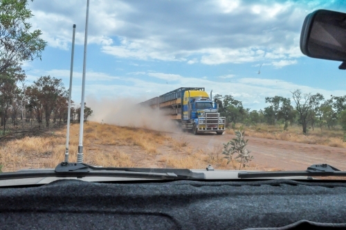 oncoming road train on a dirt road from inside the car - Australian Stock Image