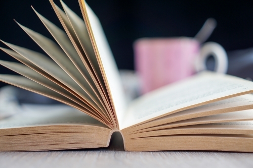 Open book with coffee cup in background - Australian Stock Image