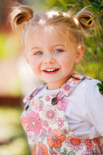 out of focus preschool child sitting on edge of garden bed in bright sunny kindergarten yard - Australian Stock Image