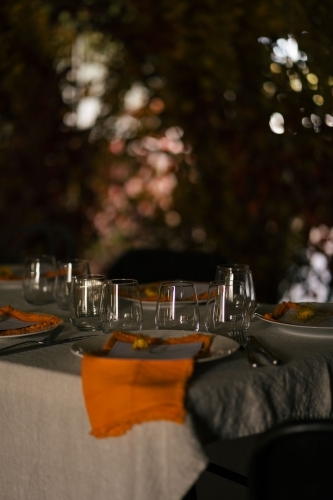 Outdoor dining table with wine glasses, plates, and cutleries