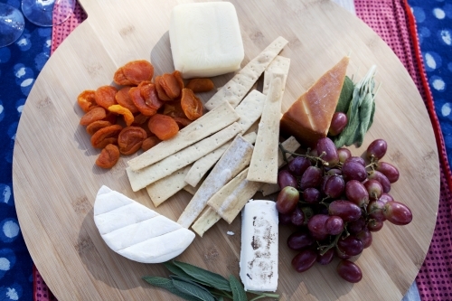 Overhead shot of cheese board on outdoor table setting - Australian Stock Image