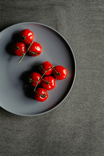 Overhead view of fresh, ripe homegrown vine picked organic heirloom red tomatoes on a plate - Australian Stock Image