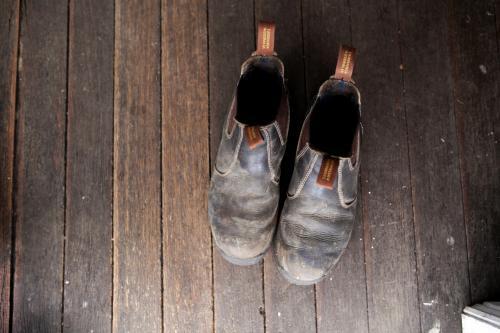 Pair of work boots from above on wooden floor - Australian Stock Image