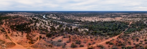 Panorama of red outback land with low green scrub - Australian Stock Image