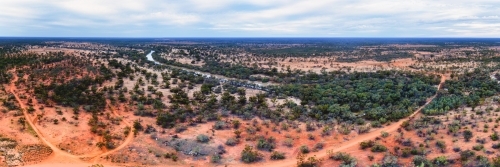 Panorama of red sand plains and mulga scrubs beside long, dusty tracks - Australian Stock Image