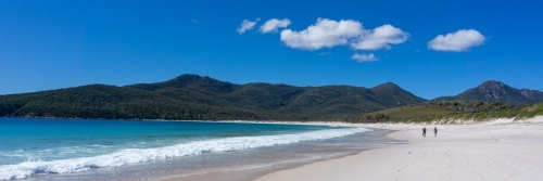 Panoramic photo of walkers along beach at Wineglass Bay - Australian Stock Image