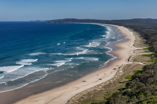 Panoramic view of calm  stretch of coastline with white sand, surf & bush - Australian Stock Image