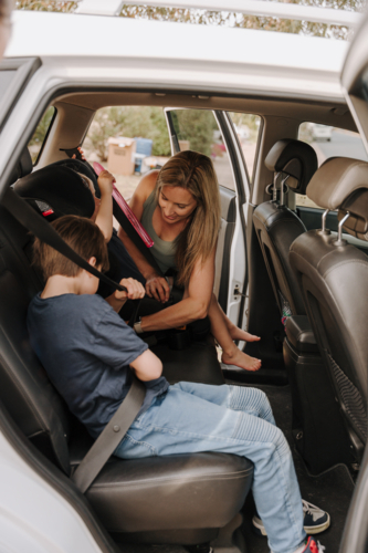 Parents helping the kids secure them in the car and booster seat. - Australian Stock Image