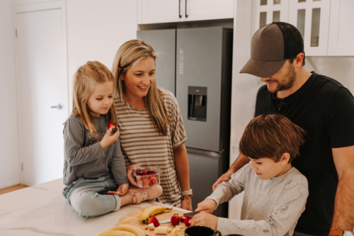 Parents teaching kids how to cut fruits in the kitchen. - Australian Stock Image