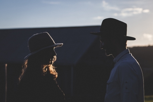 Partial silhouette of a man and woman talking in the evening - Australian Stock Image