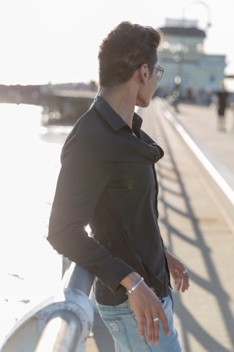 Partially backlit portrait of hispanic male leaning on pier railing