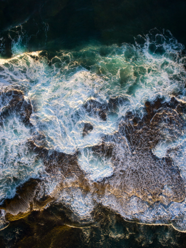 Patterns emerge on an exposed reef after crashing waves recede into the ocean - Australian Stock Image