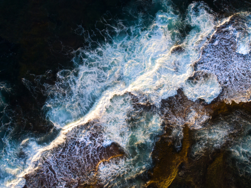 Patterns erupt from a crashing wave over an exposed reef - Australian Stock Image