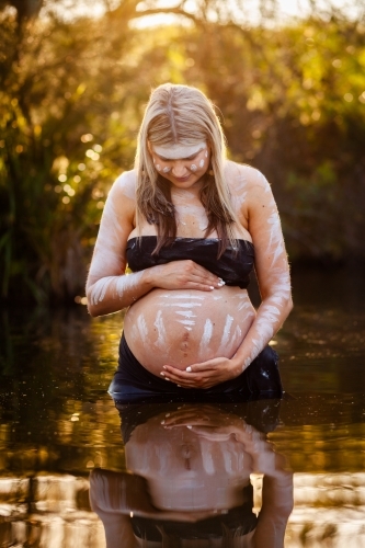 Peaceful scene with pregnant aboriginal woman in still water with reflection - Australian Stock Image