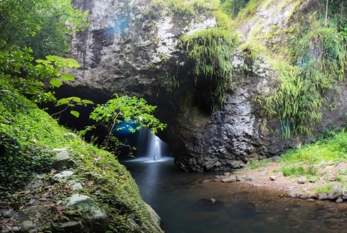 Peering in to a hidden waterfall in a cave - Australian Stock Image