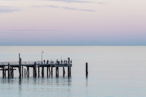 people fishing from jetty at dawn - Australian Stock Image