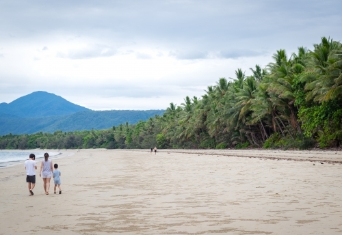 people leisurely walking along a tropical beachscape - Australian Stock Image