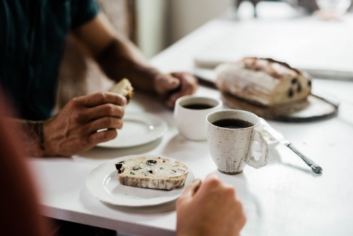 People sitting at a table drinking coffee and eating artisan bread - Australian Stock Image