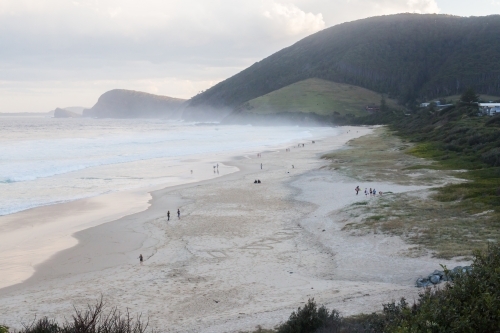 People walking along blueys beach at sunset - Australian Stock Image