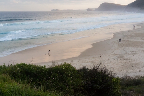 People walking along blueys beach at sunset - Australian Stock Image