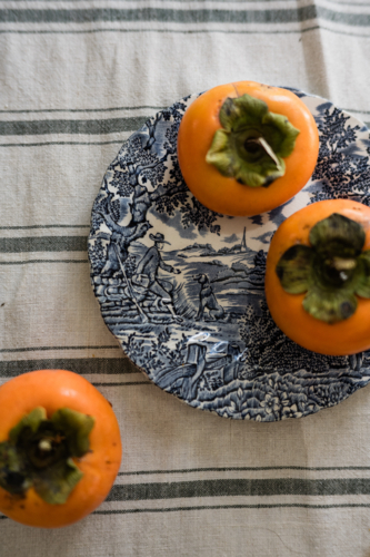 persimmons on a blue and white plate - Australian Stock Image