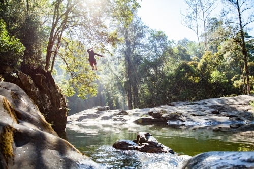 Person leaping down into deep pool of beautiful stream at Ladies Well - Australian Stock Image