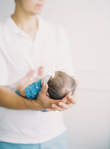 Person standing, holding baby - Australian Stock Image