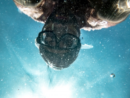 person swimming underwater wearing diving mask on a sunny day - Australian Stock Image