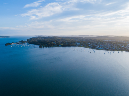 Personal recreational boats and yachts moored on distant shore of Cockle Bay in Lake Macquarie - Australian Stock Image