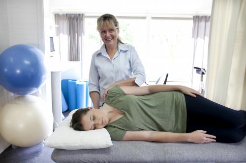 Physiotherapist treating a female patient lying on a bed