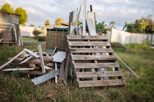 Pile of scrap wood and metal in overgrown yard - Australian Stock Image