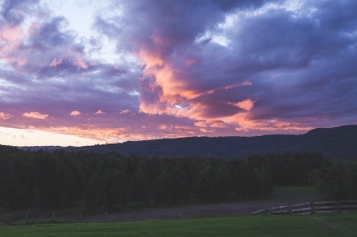 Pink and purple clouds over forest in rural Australia - Australian Stock Image