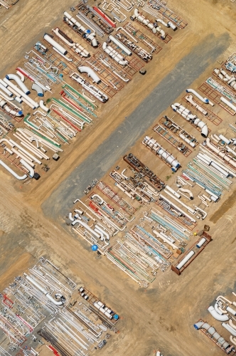 Pipes and industrial construction parts stocked on the ground for a liquefied natural gas plant. - Australian Stock Image