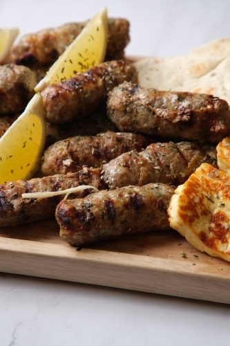 platter of grilled  sausages with herbs on top - Australian Stock Image