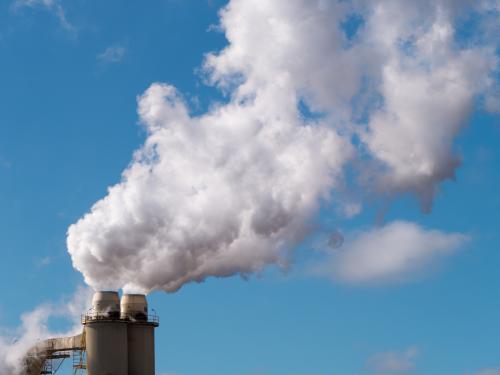 Plumes of steam rising from industrial chimneys into a blue sky - Australian Stock Image