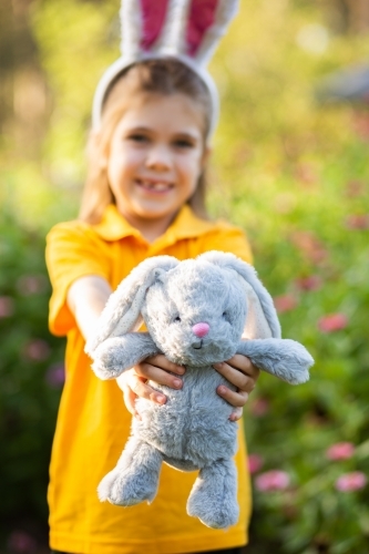 Plush rabbit toy held by a child at Easter - Australian Stock Image