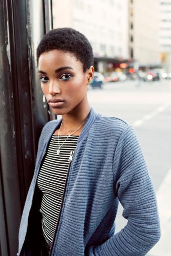 Portrait of a dark young woman leaning on a pole on the street - Australian Stock Image