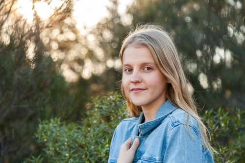 Portrait of a happy blonde girl in denim jacket outside - Australian Stock Image