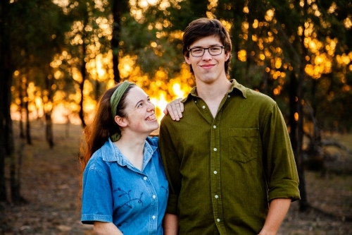 Portrait of a happy couple smiling at sunset with golden bokeh light - Australian Stock Image