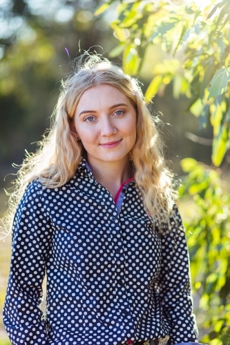 Portrait of a happy smiling blonde young adult person surrounded by gum leaves - Australian Stock Image
